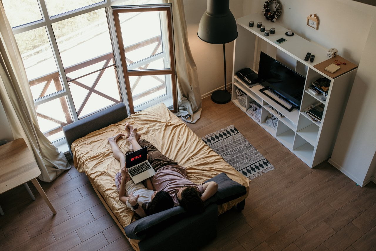 Pareja acostada con su computadora viendo series de viaje en Netflix